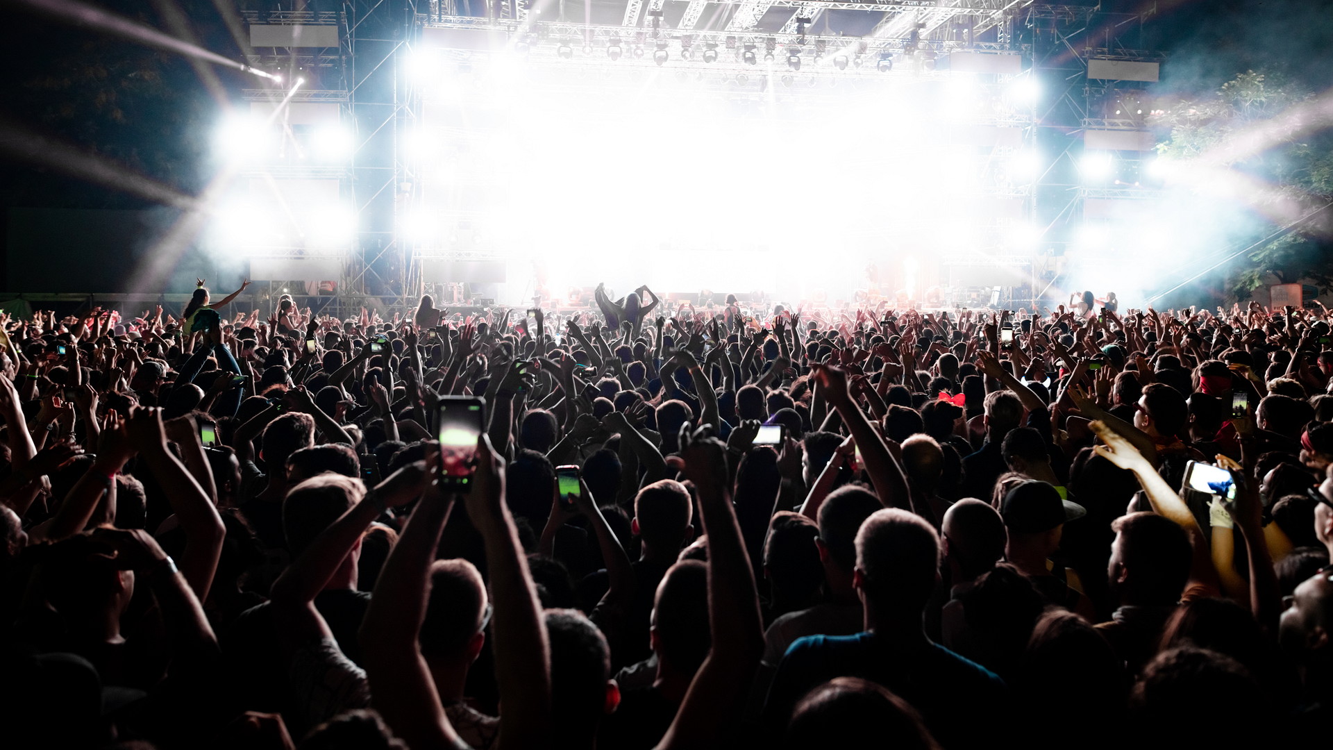 back-view-of-excited-audience-with-arms-raised-cheering-in-front-of-the-stage-at-music-concert-copy-space